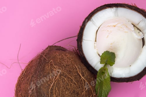 Preview: Vanilla ice cream balls in fresh coconut halves decorated with mint leaves on a pink background