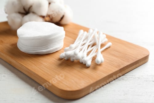 Preview: Board with cotton swabs, pads and flowers on white wooden background