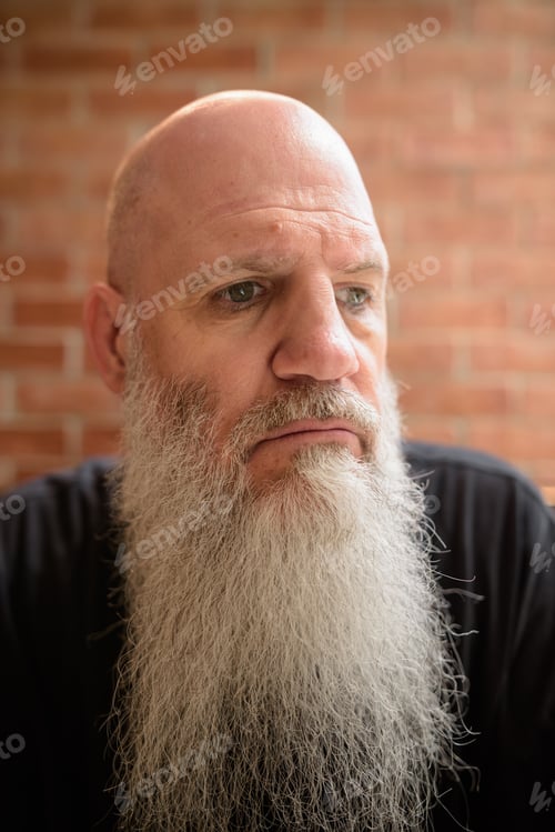 Preview: Portrait of worried mature man with long gray beard looking sad while thinking