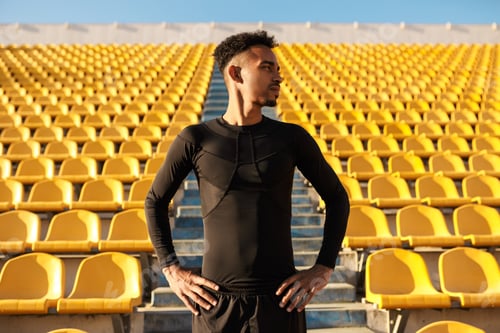 Preview: Attractive African American sportsman confidently looking aside among empty stadium seats