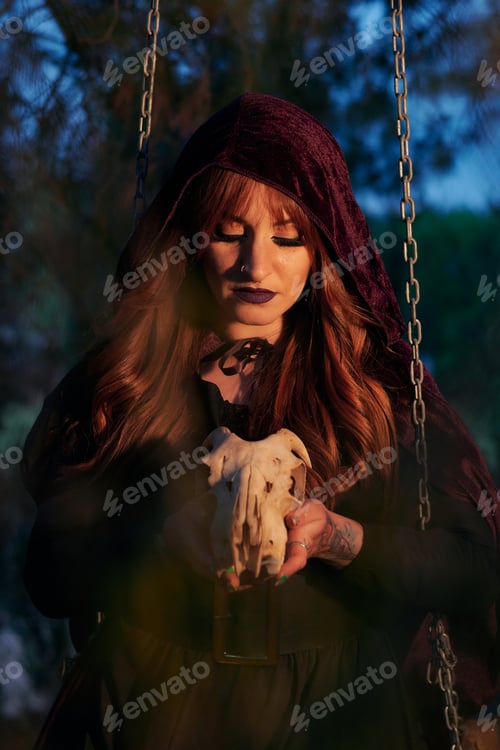 Preview: Woman disguised as a witch holding a skull in her hands