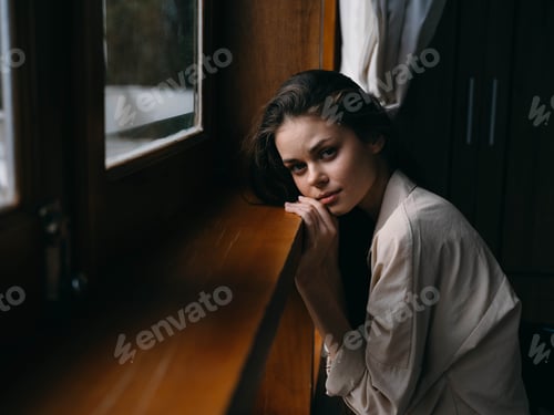 Preview: Portrait of young woman at home by window with wooden frame, autumn mood, cozy lifestyle, sleepy