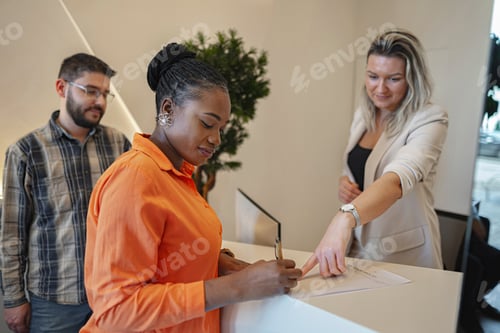 Preview: Woman Standing at Counter Signing Piece of Paper