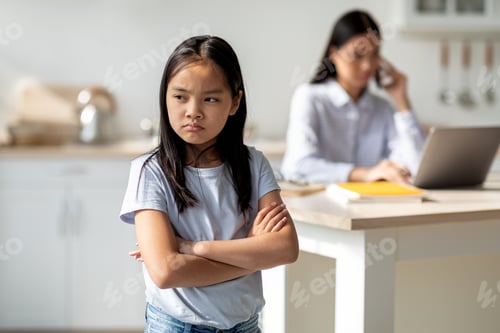 Preview: Working mom doing online job, her offended daughter feeling lonely, standing in kitchen interior