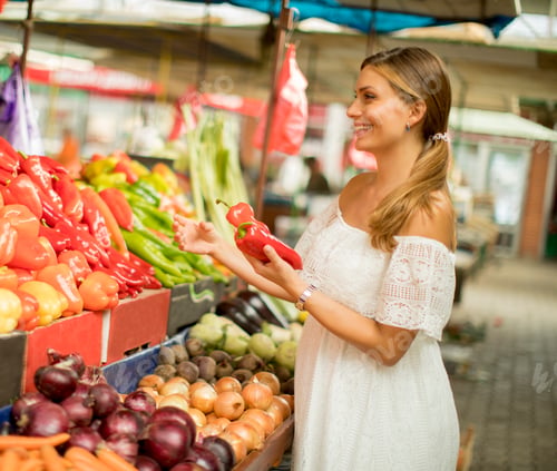 Preview: Young woman buying vegetables on the market