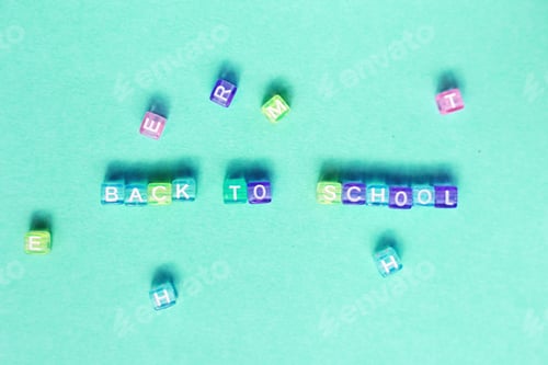 Preview: The inscription back to school made by multicolor plastic cubes on a blue green background.