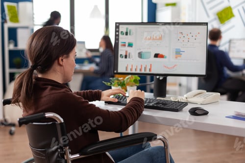 Preview: Handicapped businesswoman in wheelchair typing financial strategy working at company