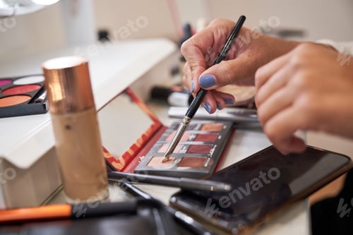 Preview: Crop woman taking colorful eyeshadow with brush