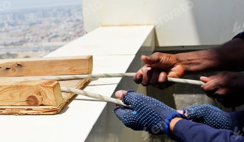 Preview: Two unrecognizable diverse men pull ropes together on the rooftop of a high rise apartment building