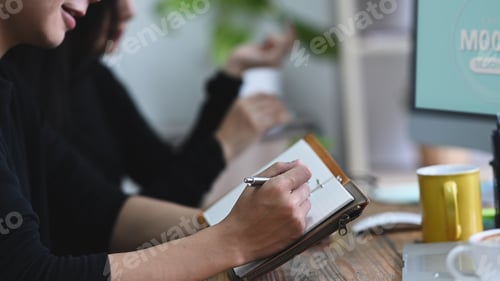 Preview: Young man sitting in creative office and making some information on notebook.
