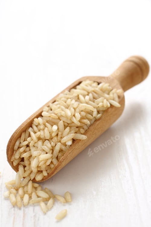 Preview: Unpolished rice in a wooden scoop on white background