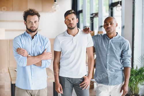 Preview: multiethnic young businessmen looking at camera while standing in office