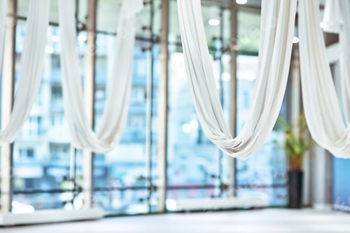 Preview: Beautiful and bright empty yoga studio with big panoramic windows, fly yoga equipment