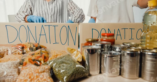 Preview: Girl volunteer wear gloves packing food and drink donation into donations paper boxes.