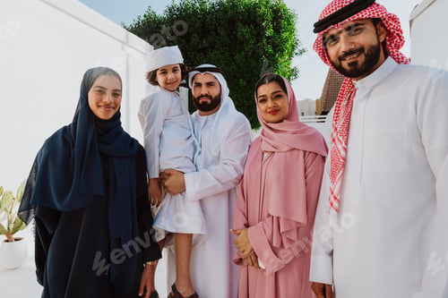 Preview: Emirati family standing together smiling in traditional attire