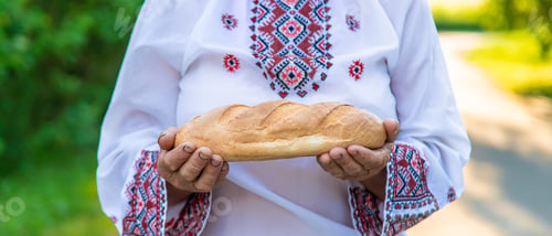 Preview: Grandmother with Ukrainian bread in her hands. Selective focus.
