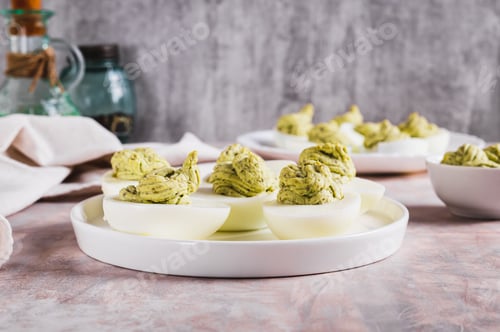 Preview: Eggs stuffed with avocado and yolk mixture on a plate on a table