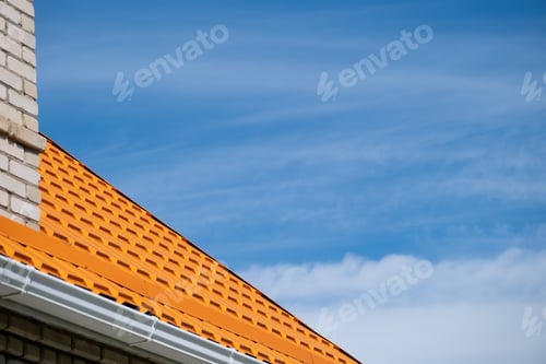 Preview: Bright orange roof of metal roofing against blue sky