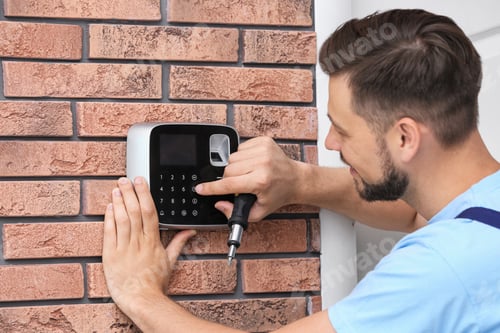 Preview: Male technician programming alarm system indoors