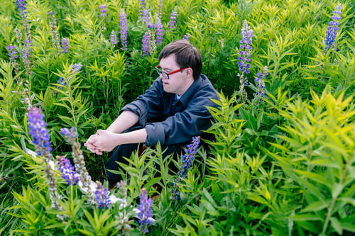 Preview: Girl with Down syndrome in pink hoodie drawing outdoors among lupines