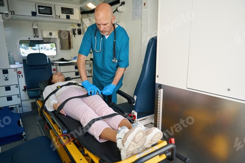 Preview: Doctor tightens seat belts on body of patient in ambulance