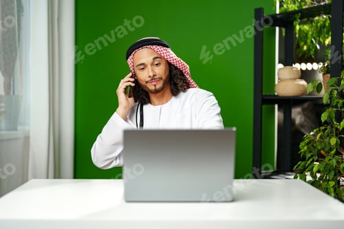 Preview: Young Arab businessman talking on the phone in the office
