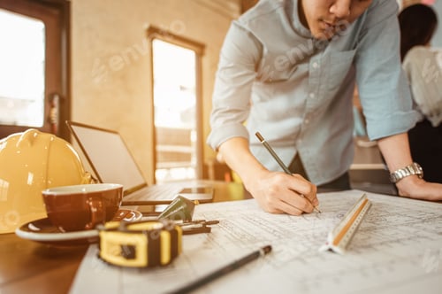 Preview: Close up of male architect hands writing model on the desk. Blurred behind team of engineer