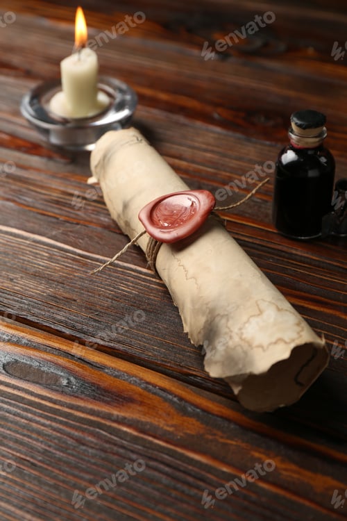 Preview: Old rolled scroll, burning candle and inkwell on wooden table, closeup