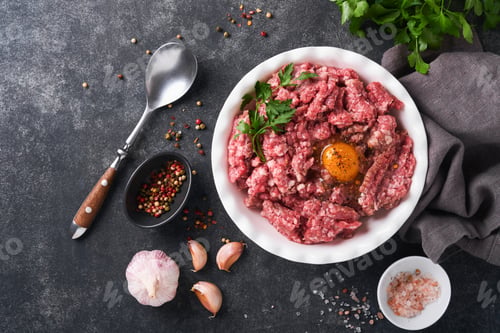 Preview: Raw minced meat. Ground meat beef, pork or lamb spices, herbs and eggs on white plate on black old c