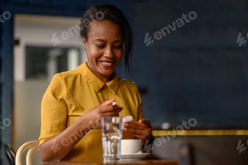 Preview: African american woman using airpods and a smartphone while sitting in a cafe
