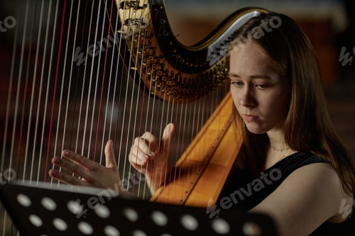Preview: Portrait of Young Woman Plucking Strings of Harp Playing Classical Music Indoors
