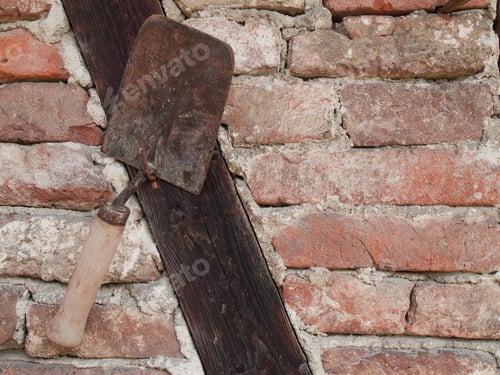 Preview: Closeup of a trowel hanging from a nail on a stone wall under the natural light