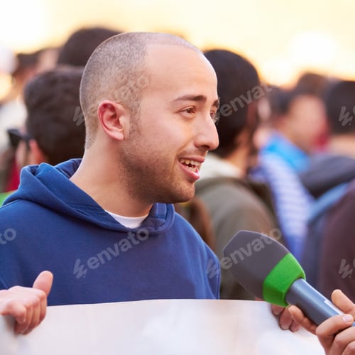 Preview: Presenting the case of the people. Shot of a protestor being interviewed at a rally.