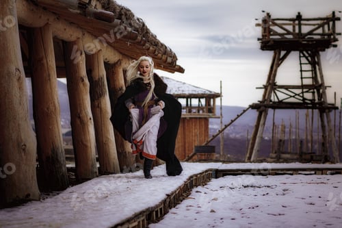 Preview: Beautiful blonde Viking dressed in a black cloak against the backdrop of the castle