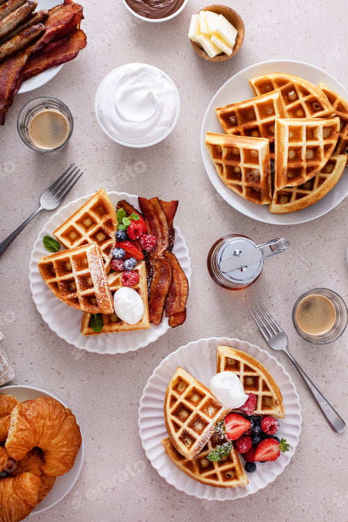 Preview: Breakfast table with waffles, bacon, breakfast sausage, croissants and berries