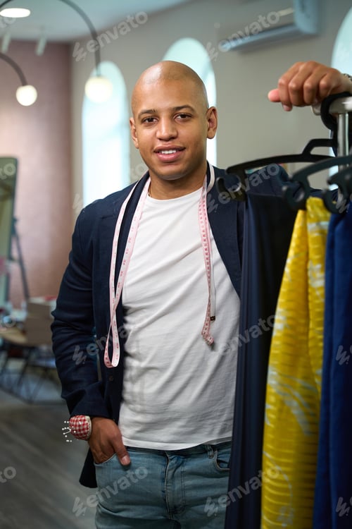 Preview: Smiling clothier posing for camera in his tailoring workshop