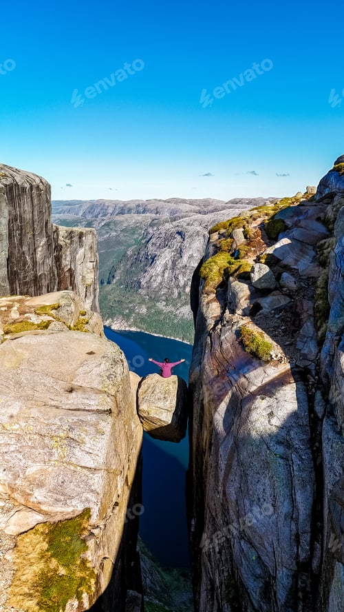 Preview: A person stands on the edge of the Kjeragbolten Pulpit Rock in Norway