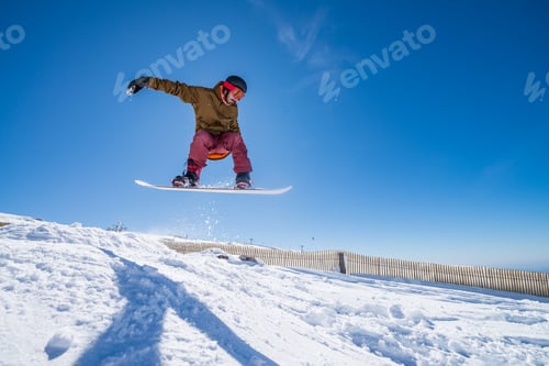 Preview: Snowboarder jumping against blue sky