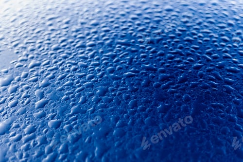 Preview: Condensed dewdrops on the smooth blue surface of a metallic car.