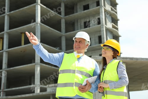 Preview: Professional engineer and foreman with tablet in safety equipment at construction site