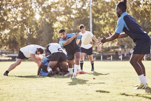 Preview: Mixed race rugby player making a pass to an african american teammate during a match outside on a f