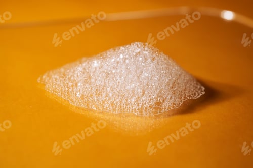 Preview: White foam from shampoo or shower gel on a bright yellow background.