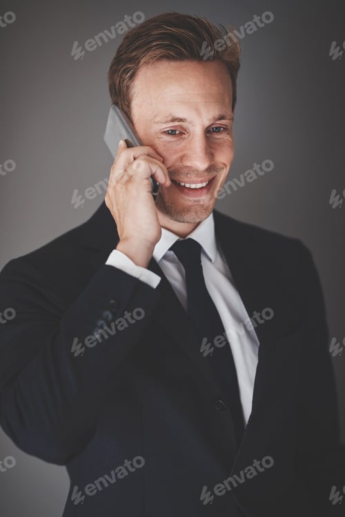 Preview: Smiling businessman talking on his cellphone against a gray background