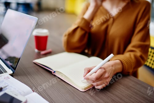 Preview: Crop woman taking notes in notebook