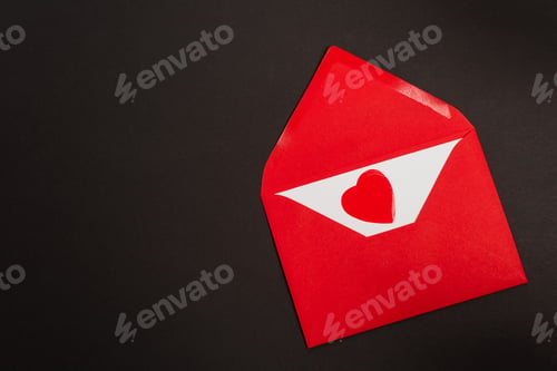 Preview: top view of red envelope with love letter and paper cut heart isolated on black