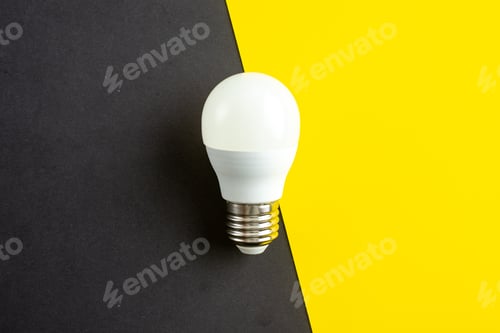 Preview: Top view of standard incandescent light bulb on black yellow mixed colors background with free space