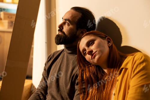 Preview: Happy man and woman resting on the floor among cardboard boxes