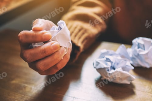 Preview: A woman screwed up papers by hand on wooden table