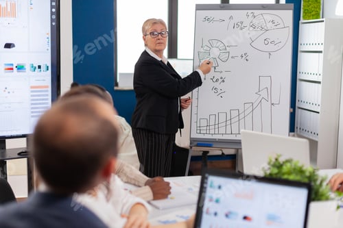 Preview: Mature businesswoman writing on white board, presenting sales evolution