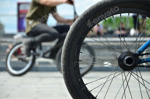 Preview: A BMX bike wheel against the backdrop of a blurred street with cycling riders
